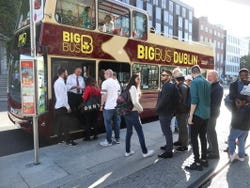 A group of tourists lining up to board a Big Bus sightseeing bus in Dublin